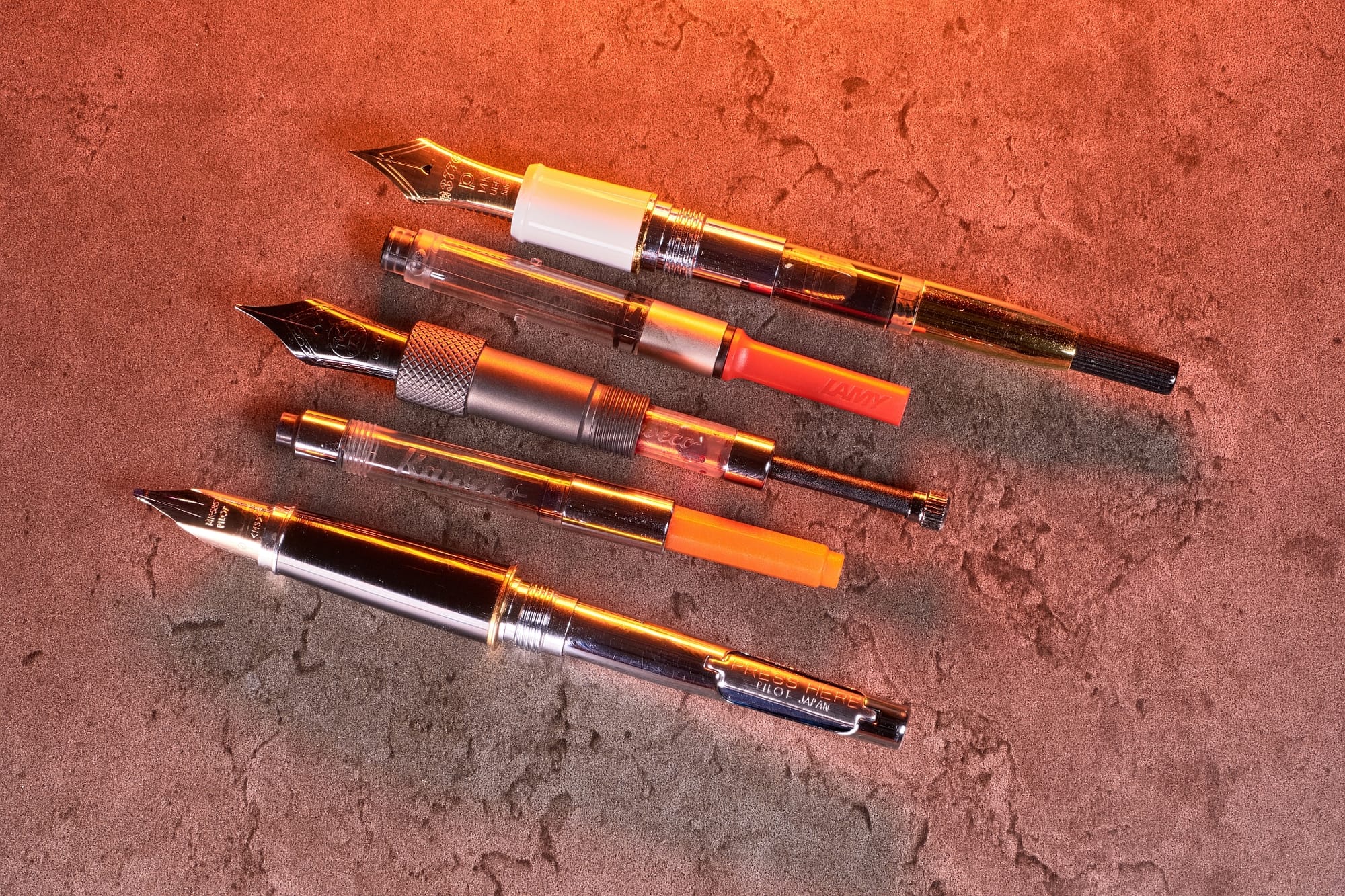 Photo of 3 different types of converters attached to pens, plus 2 different loose converters.
