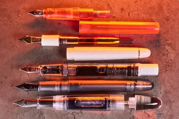 Photo of 5 fountain pens with their caps off, each with a different filling system, arranged horizontally top to bottom.